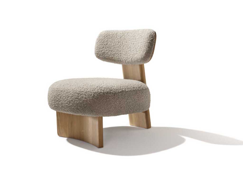 Moderner Lounge-Sessel mit einem minimalistischen Design. Der Sessel hat eine breite, abgerundete Sitzfläche und eine schmale, leicht gebogene Rückenlehne, beide gepolstert mit einem weichen, cremefarbenen Stoff in Bouclé-Optik. Die Polsterung wirkt einladend und komfortabel. Der Sessel steht auf massiven Holzbeinen, die leicht schräg angebracht sind und dem Sessel eine stabile und zugleich elegante Basis verleihen. Das Design des Sessels kombiniert natürlichen Holzcharme mit modernen, gemütlichen Polstermaterialien, was ihn zu einer perfekten Wahl für stilvolle und entspannte Wohnräume macht.